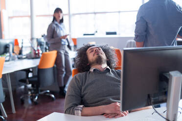 A time for relax. Young tired casual businessman relaxing at the desk in his office - INGF12862