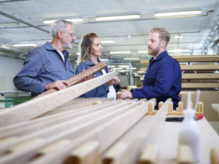 Carpenters discussing over wooden plank in industry - CVF02528