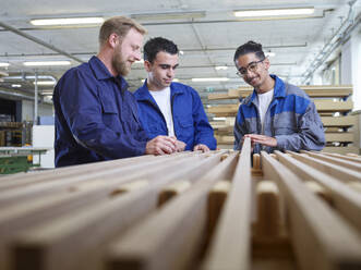 Lächelnde Auszubildende bei der Prüfung von Holzbrettern in einer Fabrik - CVF02529