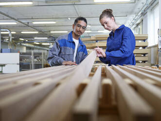 Auszubildende prüfen Holzbohlen in der Werkstatt - CVF02530