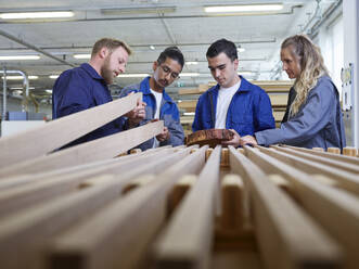 Carpenters and trainees examining wooden planks in factory - CVF02545