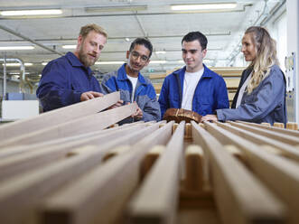 Carpenter holding wooden plank and explaining trainees in factory - CVF02546