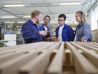 Schreiner erklärt Auszubildenden die Holzbretter in der Fabrik - CVF02550