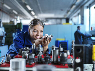 Lächelnder Auszubildender beim Erlernen der Steuerung von CNC-Werkzeugen in einer Fabrik - CVF02553