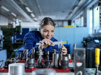 Metallarbeiter bei der Überprüfung eines CNC-Werkzeugs mit einem Messschieber im Werk - CVF02554