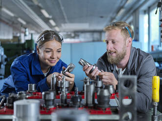Trainee with metal worker looking at CNC tools in factory - CVF02560