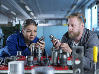 Trainee with metal worker examining CNC tools in factory - CVF02561