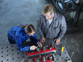 Metal worker and trainee measuring CNC tool with caliper in factory - CVF02562