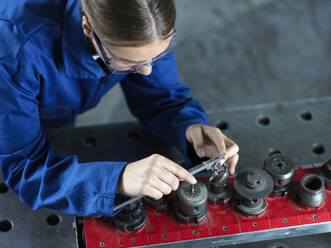 Metallarbeiter beim Messen eines CNC-Werkzeugs mit einem Messschieber in einer Fabrik - CVF02563