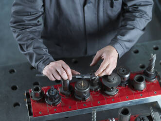Metallarbeiter beim Prüfen eines CNC-Werkzeugs mit einem Messschieber in der Fabrik - CVF02564