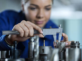 Auszubildender misst CNC-Werkzeug mit Messschieber in der Fabrik - CVF02566