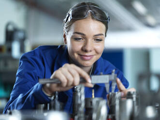 Lächelnder Industriearbeiter bei der Überprüfung eines CNC-Werkzeugs in einer Fabrik - CVF02568