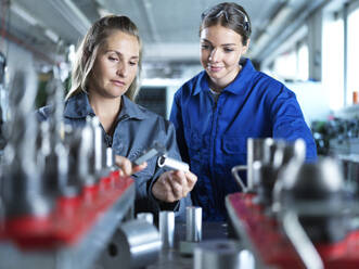 Industriearbeiter, der einem Auszubildenden in der Fabrik das Messen von CNC-Werkzeugen beibringt - CVF02575