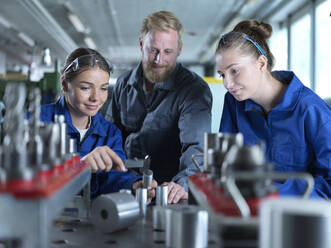 Auszubildende lernen mit Industriearbeitern im Werk das Messen von CNC-Werkzeugen - CVF02583