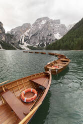 Wooden boats on lake by snow covered mountain - MMPF00923