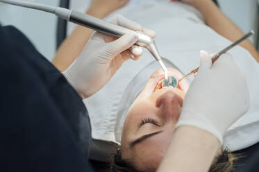 Dentist with dental drill examining patient's teeth at clinic - PGF01646