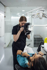 Orthodontist examining patient's teeth through microscope in examination room - PGF01653