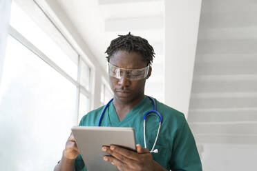 Junger Arzt trägt eine intelligente Brille und benutzt einen Tablet-PC im Krankenhaus - VRAF00195