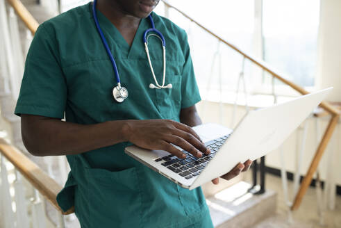 Medizinstudent benutzt Laptop im Treppenhaus eines Krankenhauses - VRAF00201