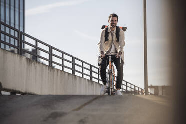 Man riding bicycle in front of sky on sunny day - UUF30506