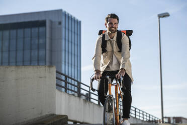 Mann fährt Fahrrad vor einem Gebäude und Himmel - UUF30507