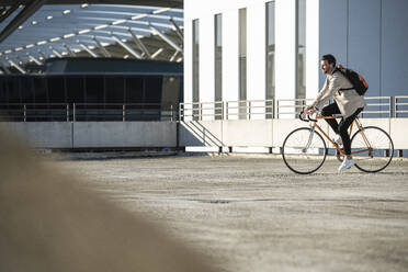 Man riding bicycle in parking lot on sunny day - UUF30509