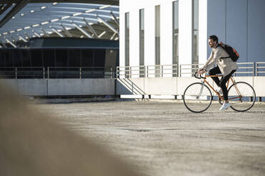 Mann fährt Fahrrad auf einem Parkplatz an einem sonnigen Tag - UUF30509