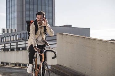 Mann mit Rucksack auf dem Fahrrad vor einem Gebäude - UUF30511