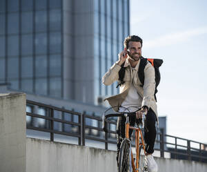 Mann fährt Fahrrad vor einem Gebäude - UUF30513