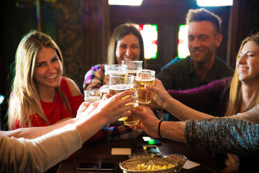 Eine Gruppe fröhlicher Freunde feiert in einer Bar - Junge Leute trinken Bier - DMDF05529