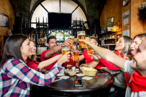 Gruppe von Freunden, die ihre Fußballmannschaft im Pub anfeuern - Gruppe von Fußballfans, die sich in einer Bar treffen und feiern - DMDF05532