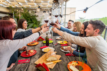 Group of happy friends bonding at home - Young adults having lunch and spending time together on a rooftop balcony, cooking meat on barbecue - DMDF05555