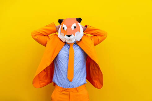 Cooler Mann trägt 3d Origami-Maske mit stilvollen farbigen Kleidung - Kreatives Konzept für die Werbung, Tierkopf Maske tun lustige Dinge auf bunten Hintergrund - DMDF05582