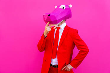 Cooler Mann trägt 3d Origami-Maske mit stilvollen farbigen Kleidung - Kreatives Konzept für die Werbung, Tierkopf Maske tun lustige Dinge auf bunten Hintergrund - DMDF05597
