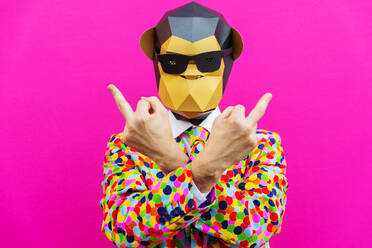 Happy man with funny low poly mask on colored background - Creative conceptual idea for advertising,adult with low-poly origami paper mask doing funny poses - DMDF05636