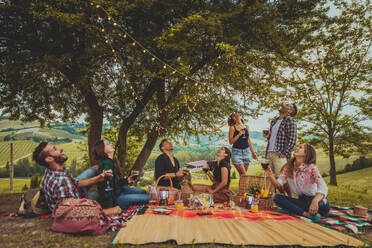 Group of young happy friends having pic-nic outdoors - People having fun and celebrating while grilling ata barbacue party in a countryside - DMDF05664