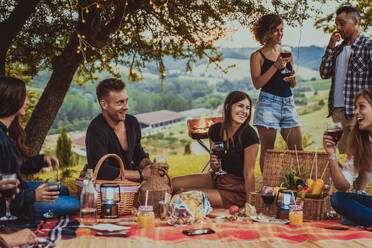 Group of young happy friends having pic-nic outdoors - People having fun and celebrating while grilling ata barbacue party in a countryside - DMDF05669