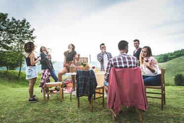 Group of young happy friends having pic-nic outdoors - People having fun and celebrating while grilling ata barbacue party in a countryside - DMDF05693