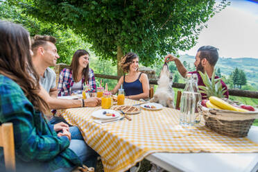 Fröhliche Gruppe von Freunden beim Frühstück in einem Bauernhaus - Junge Leute essen im Garten, Konzepte über gesunde Lebensweise und Ernährung - DMDF05715