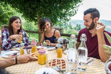 Fröhliche Gruppe von Freunden beim Frühstück in einem Bauernhaus - Junge Leute essen im Garten, Konzepte über gesunde Lebensweise und Ernährung - DMDF05718