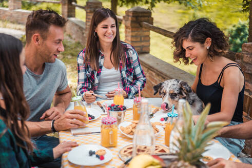 Happy cheerful group of friends having breakfast in a farmhouse - Young people eating in the garden, concepts about healthy lifestyle and food - DMDF05719