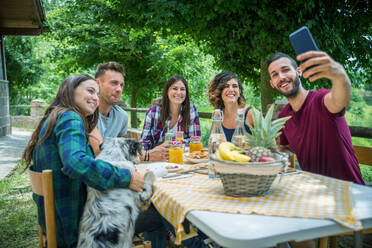 Group of happy people doing breakfast outdoors in a traditional countryside - Friends eating snacks in the garden - DMDF05720