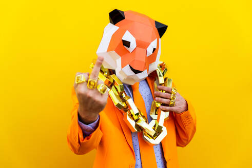Cooler Mann trägt 3d Origami-Maske mit stilvollen farbigen Kleidung - Kreatives Konzept für die Werbung, Tierkopf Maske tun lustige Dinge auf bunten Hintergrund - DMDF05723