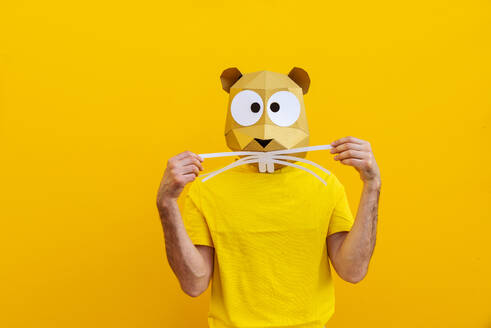 Cooler Mann trägt 3d Origami-Maske mit stilvollen farbigen Kleidung - Kreatives Konzept für die Werbung, Tierkopf Maske tun lustige Dinge auf bunten Hintergrund - DMDF05751
