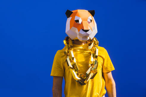 Cooler Mann trägt 3d Origami-Maske mit stilvollen farbigen Kleidung - Kreatives Konzept für die Werbung, Tierkopf Maske tun lustige Dinge auf bunten Hintergrund - DMDF05759
