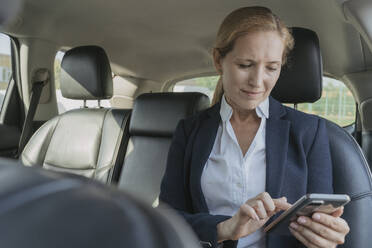 Businesswoman using smart phone in car - OSF02156