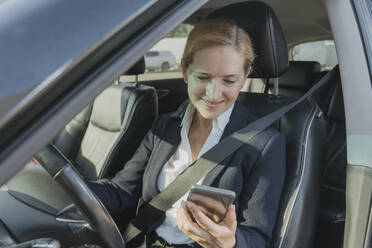 Smiling businesswoman using mobile phone in car - OSF02158