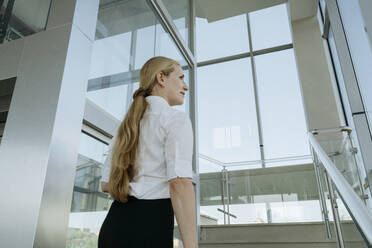 Businesswoman walking on steps in office - OSF02163