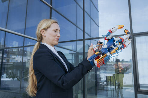 Female architect holding robotic arm near office building - OSF02172