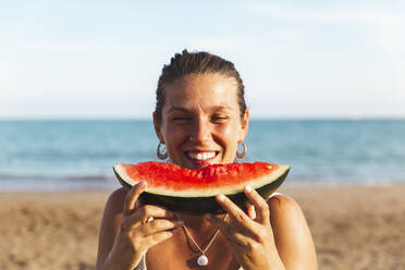 Happy woman enjoying watermelon at beach - PCLF00715